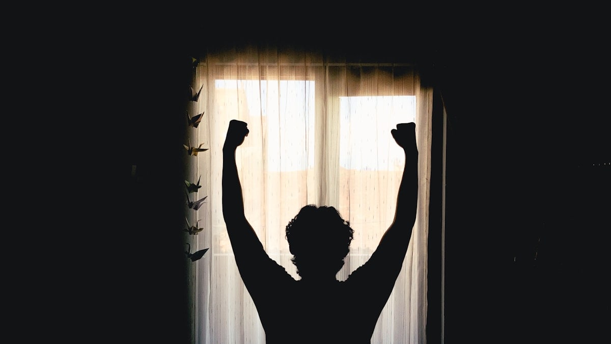 Silhouette of person with arms raised in victory